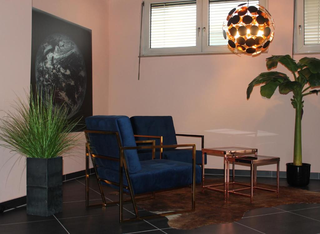 フェルバッハにあるBLUE SKY-Suiteの椅子2脚、テーブル1台、鉢植えの植物が備わるお部屋