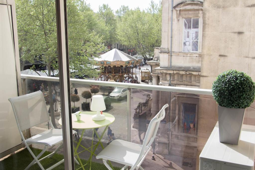 - un balcon avec des chaises blanches et une table dans l'établissement Cosy and large flat in the hypercentre of Avignon Provence - Welkeys, à Avignon