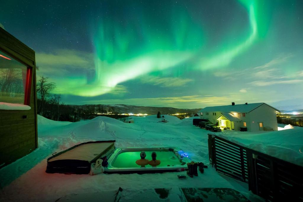 - une vue sur l'aurore au-dessus d'une cour enneigée avec une piscine dans l'établissement Aurora Borealis Observatory, à Silsand
