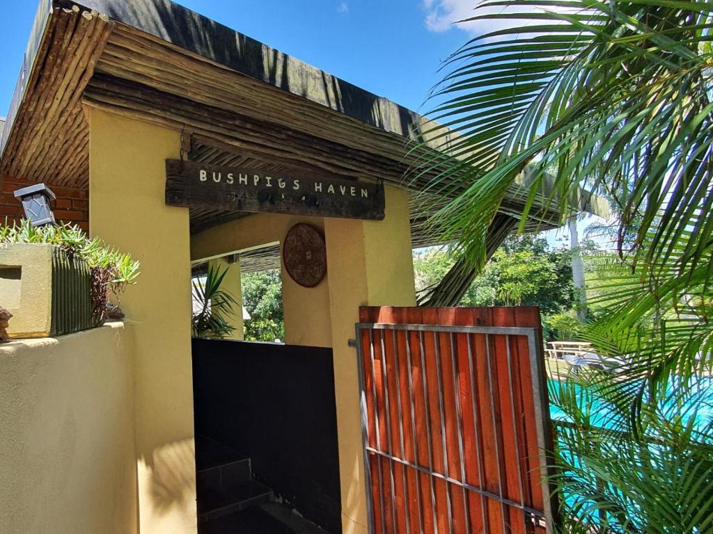 un bâtiment avec une porte en bois et un panneau dans l'établissement Bushpigs Haven, à St Lucia