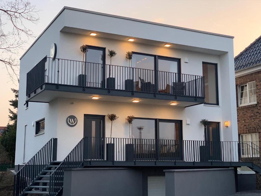 ein weißes Haus mit einem Balkon und einer Treppe in der Unterkunft Ambiente Apartments in Naumburg