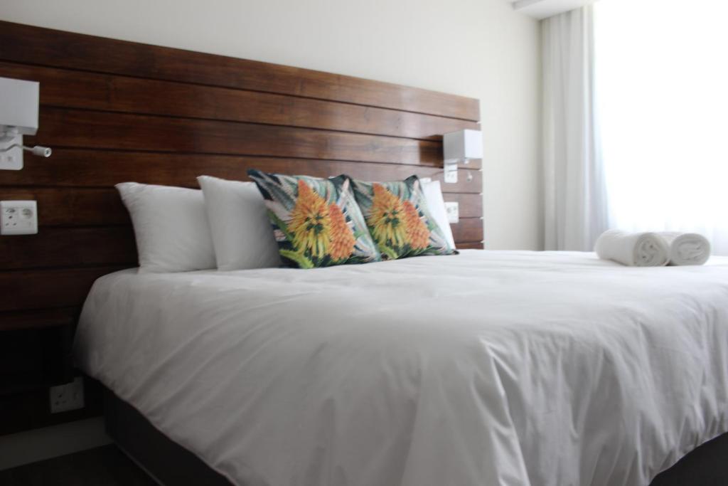 a bedroom with a large white bed with a wooden headboard at Luxe-Molen Boutique Hotel in Queenstown