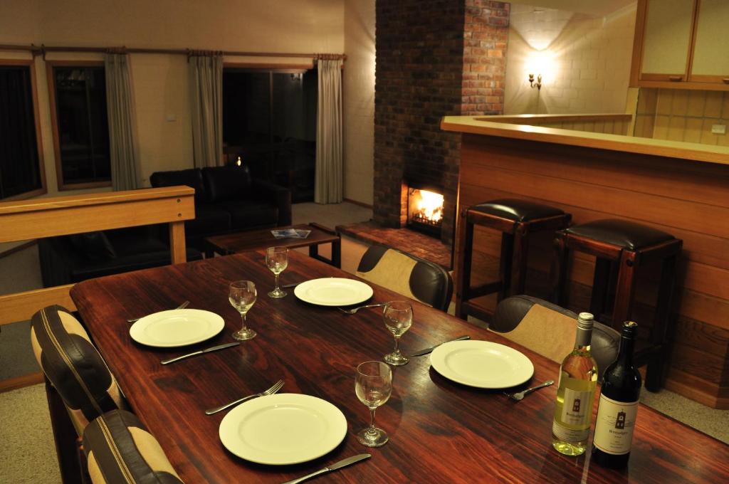 a wooden table with white plates and wine glasses at Salzburg Apartments in Perisher Valley