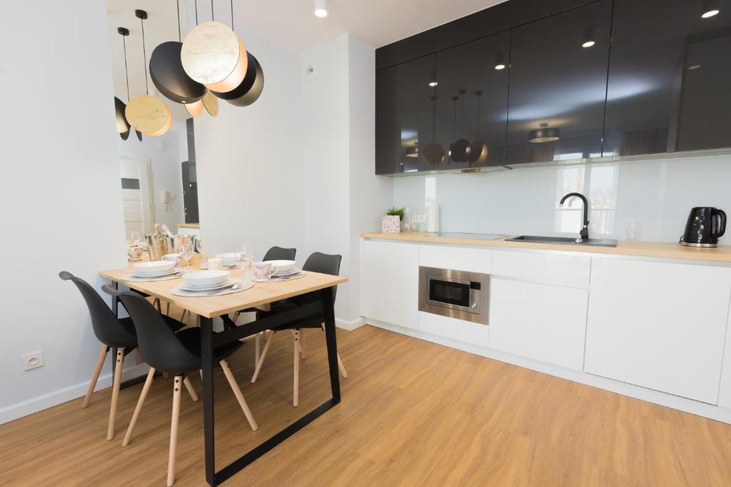 a kitchen with a wooden table and black and white cabinets at Maloves Apartment NETFLIX in Łódź