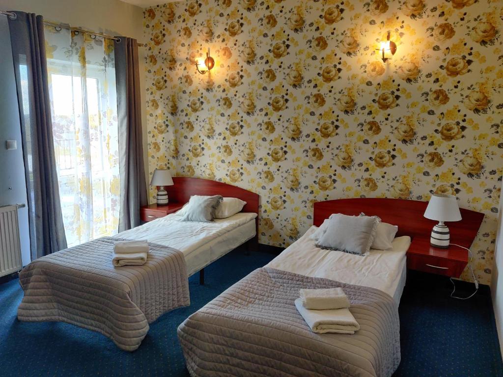 2 camas en una habitación de hotel con papel de pared amarillo en Sosnowe Zacisze Barszczewo, en Choroszcz