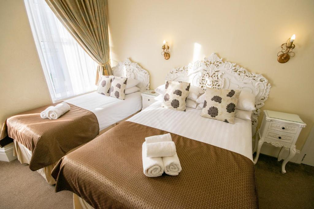 a bedroom with two beds with towels on them at Summerlands Guest House in Torquay