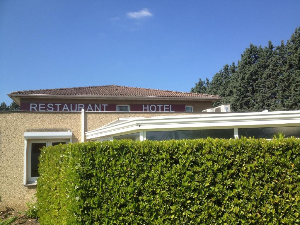 a hotel with a hedge in front of a building at Hôtel du Moulin à Vent in Vénissieux