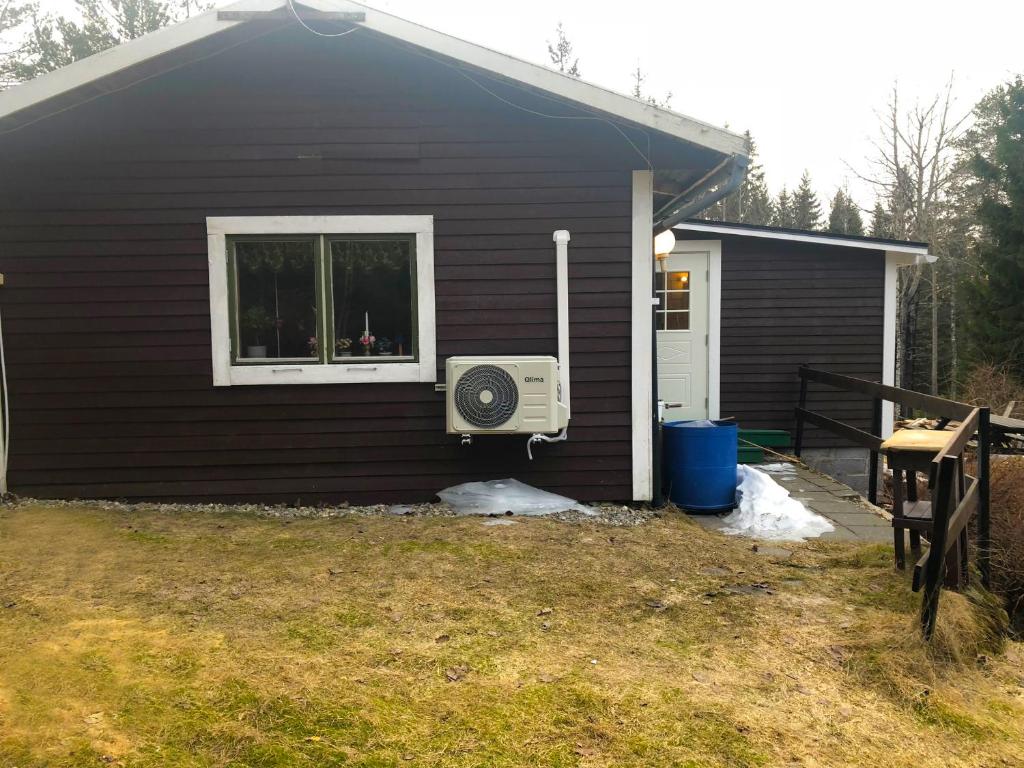 uma casa preta com uma ventoinha ao lado de uma janela em Paradiset stugan i fin skogen em Hällefors