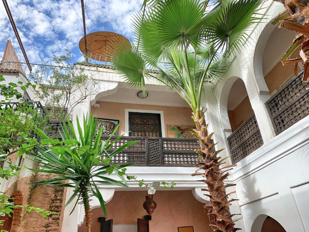 a building with palm trees and a balcony at Riad Rockech in Marrakech