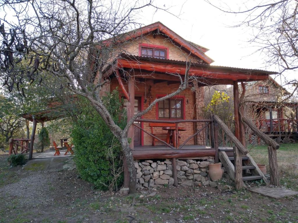 a log cabin with a porch and a tree at Los Arbolitos Cabañas y Aparts in Santa Rosa de Calamuchita