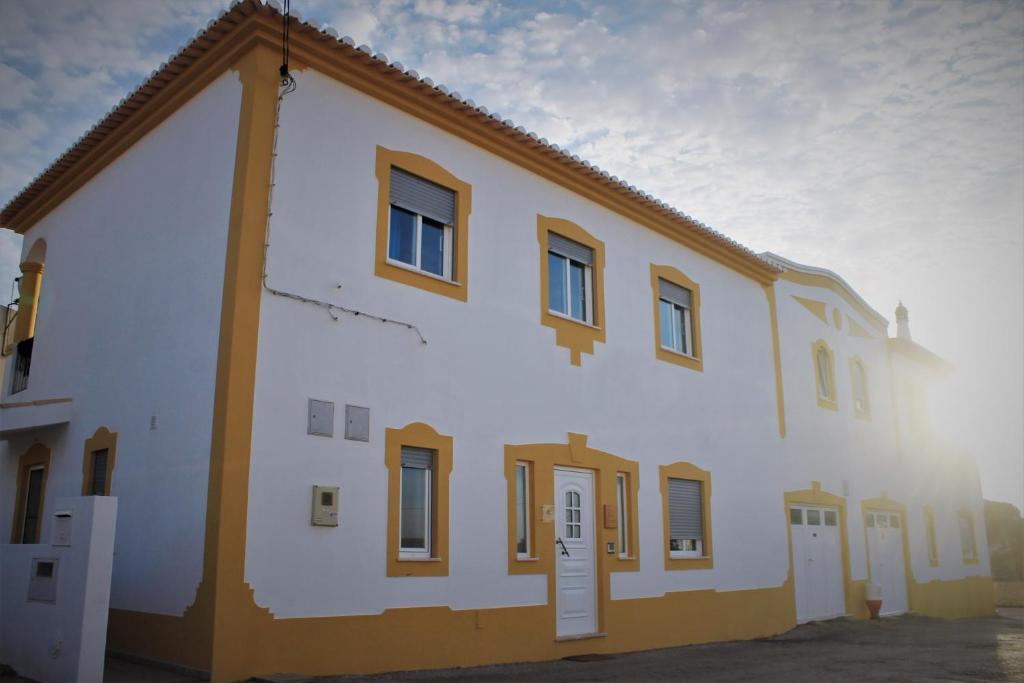 un edificio blanco con ventanas marrones y un cielo en Local Guesthouse en Sagres