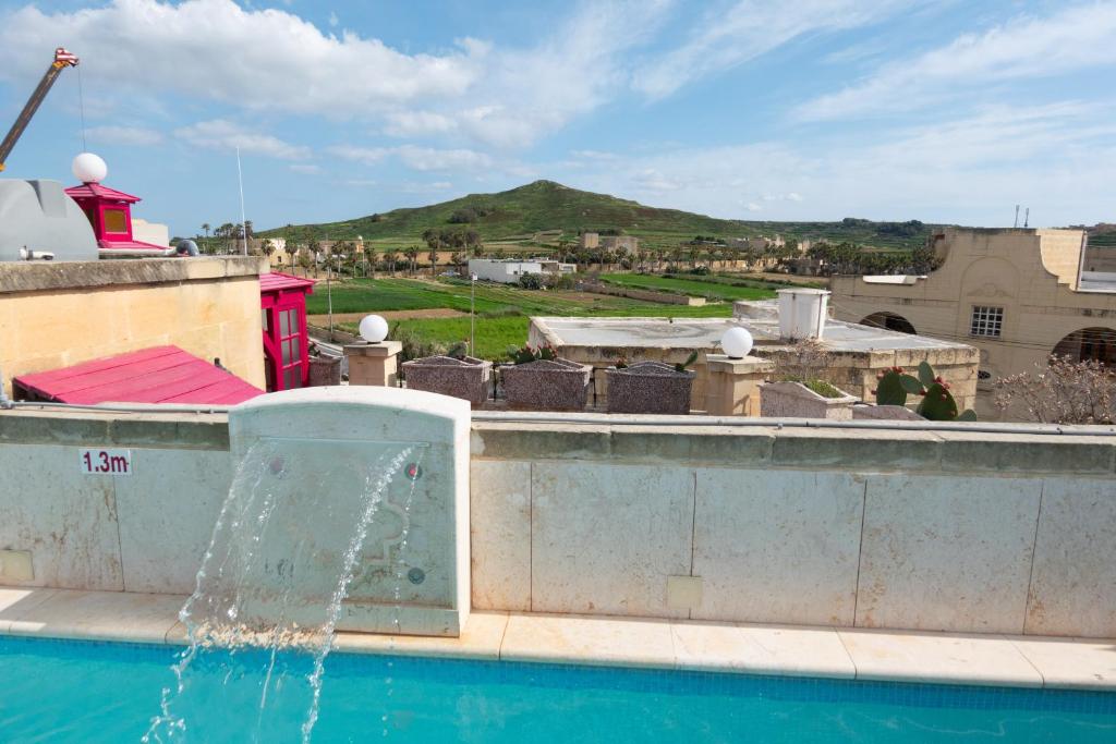 une fontaine sur le côté d'un bâtiment à côté d'une piscine dans l'établissement Prickly Pear Holiday Home No. 3, à San Lawrenz