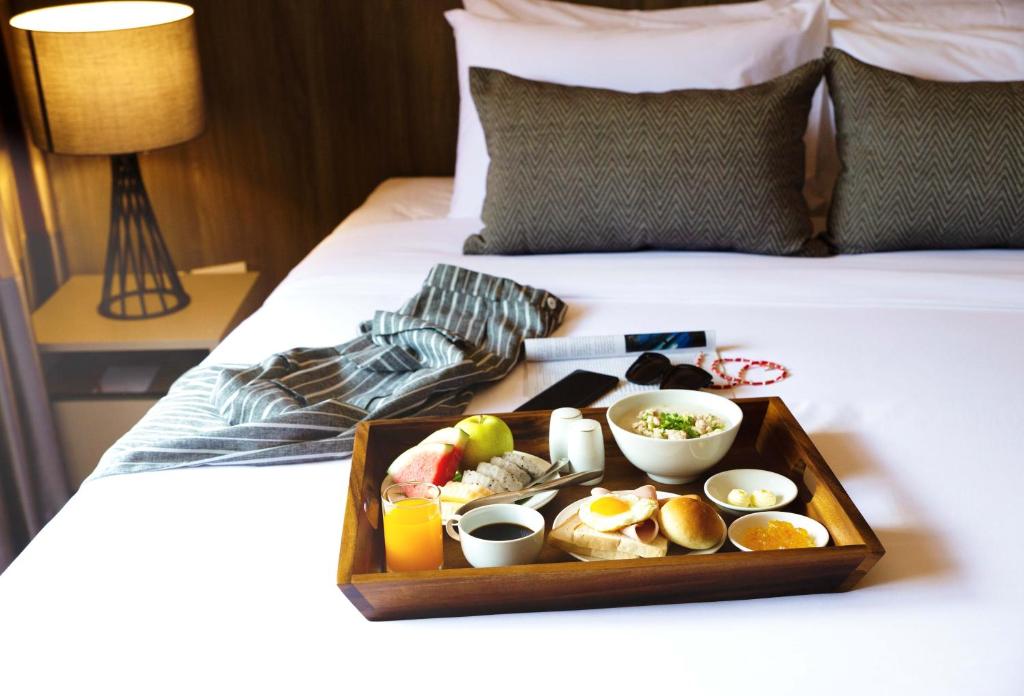 a tray of food sitting on a bed at Jazzotel Bangkok- SHA Extra Plus in Bangkok