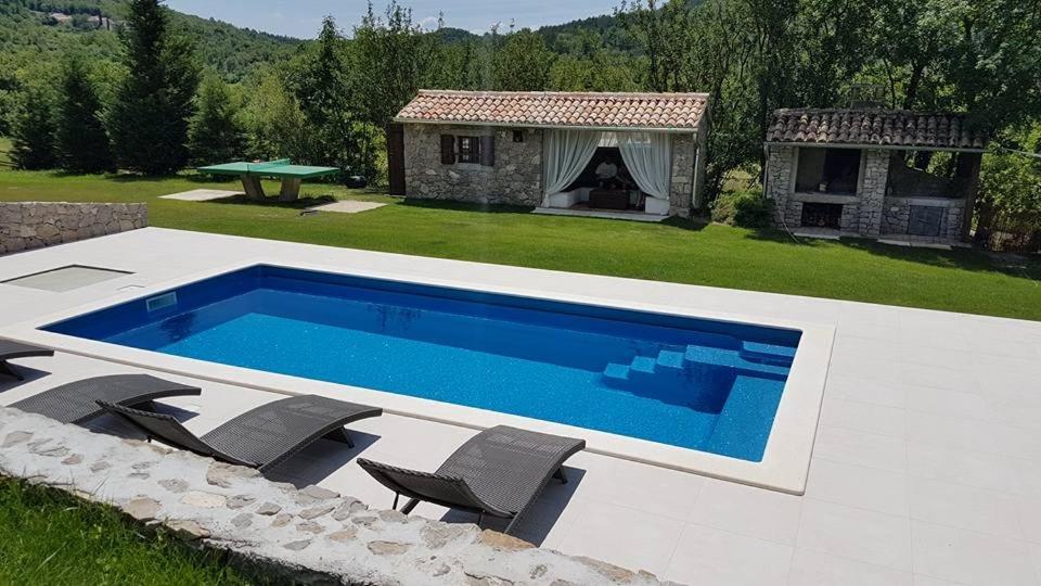 a swimming pool with chairs next to a house at Poolhouse Roc (3458) in Roč