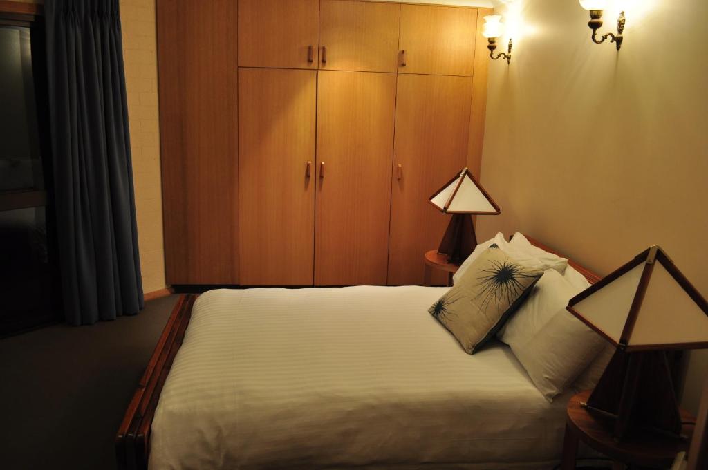 a bedroom with a bed with a cabinet and two lamps at Salzburg Apartments in Perisher Valley