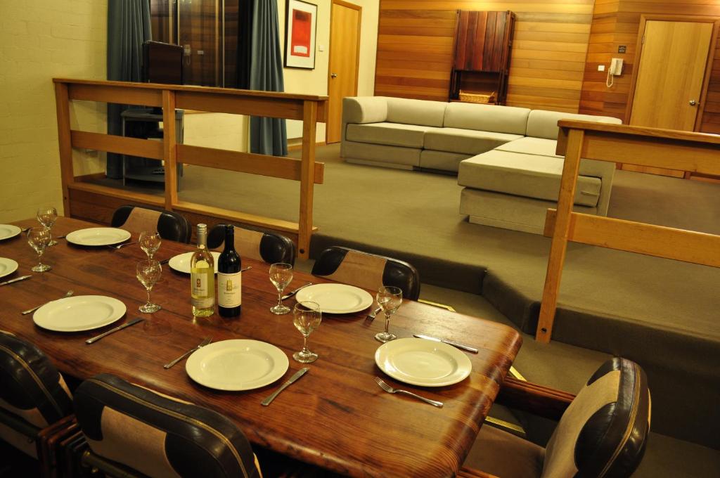 a wooden table with wine glasses and a couch at Salzburg Apartments in Perisher Valley