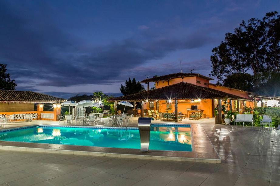 a pool in front of a house at night at Hotel Fazenda Colibri in Amargosa