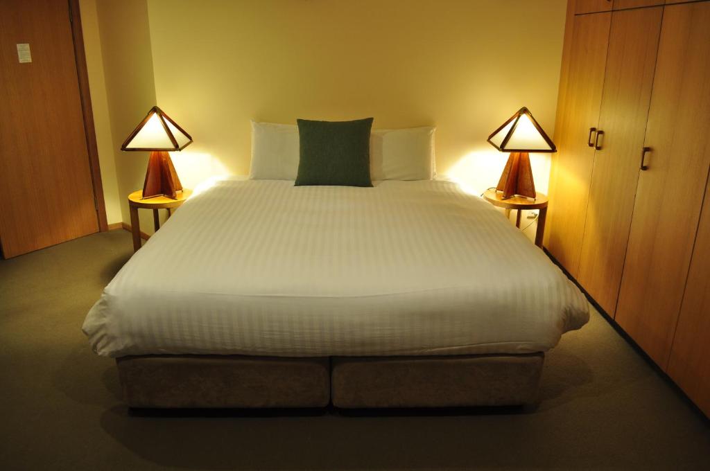 a bedroom with a large white bed with two lamps at Salzburg Apartments in Perisher Valley