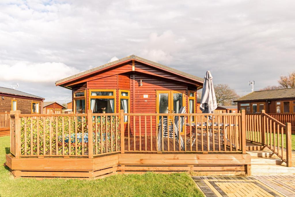 een houten hut met een poort en een terras bij Flamingo Lodge With Hot Tub in Malton