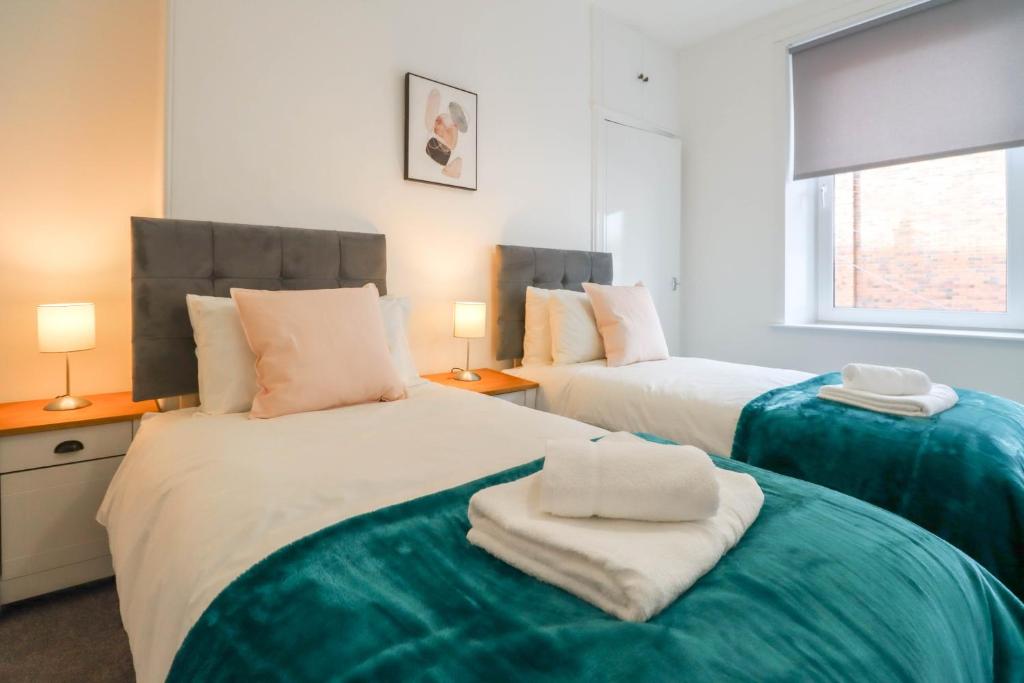two beds with towels on them in a bedroom at Largs Coastal Apartment in Largs