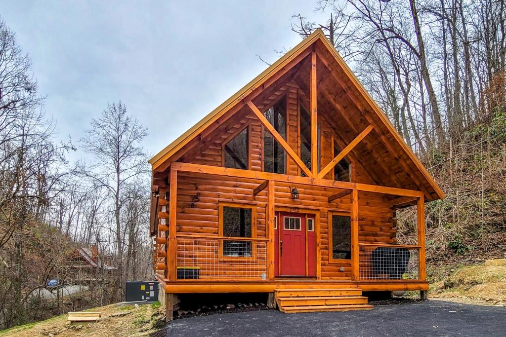a log cabin with a red door on a hill at Knotty Escape in Gatlinburg