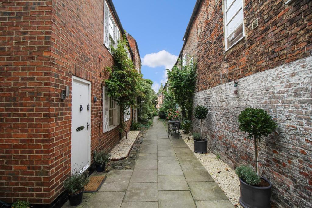 an alley between two brick buildings with potted plants at The Mews Cottage, with parking, Yarm in Yarm