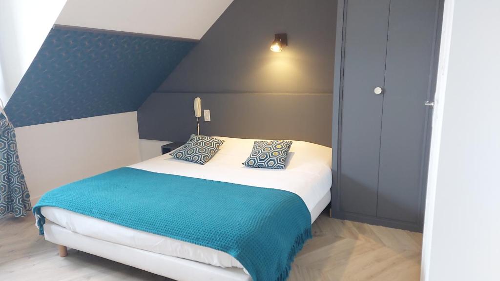 a bedroom with a bed with blue and white at Logis Hôtel Vannes Nord Le Clos Des Hortensias in Locqueltas