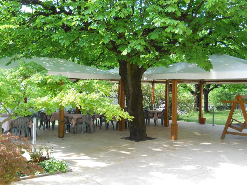 un padiglione con tavoli e sedie sotto un albero di Albergo Ristorante Aquila a Sulzano