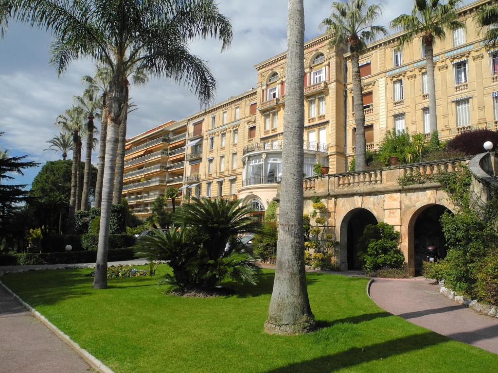 カンヌにある90m2 Apartement - Les Palmiers de Cannesの公園前のヤシの木がある建物