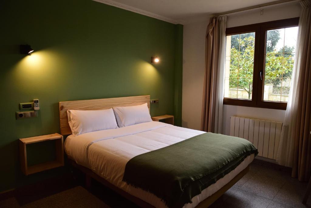 a bedroom with a large bed with a green wall at Hotel Vijanera in Galizano