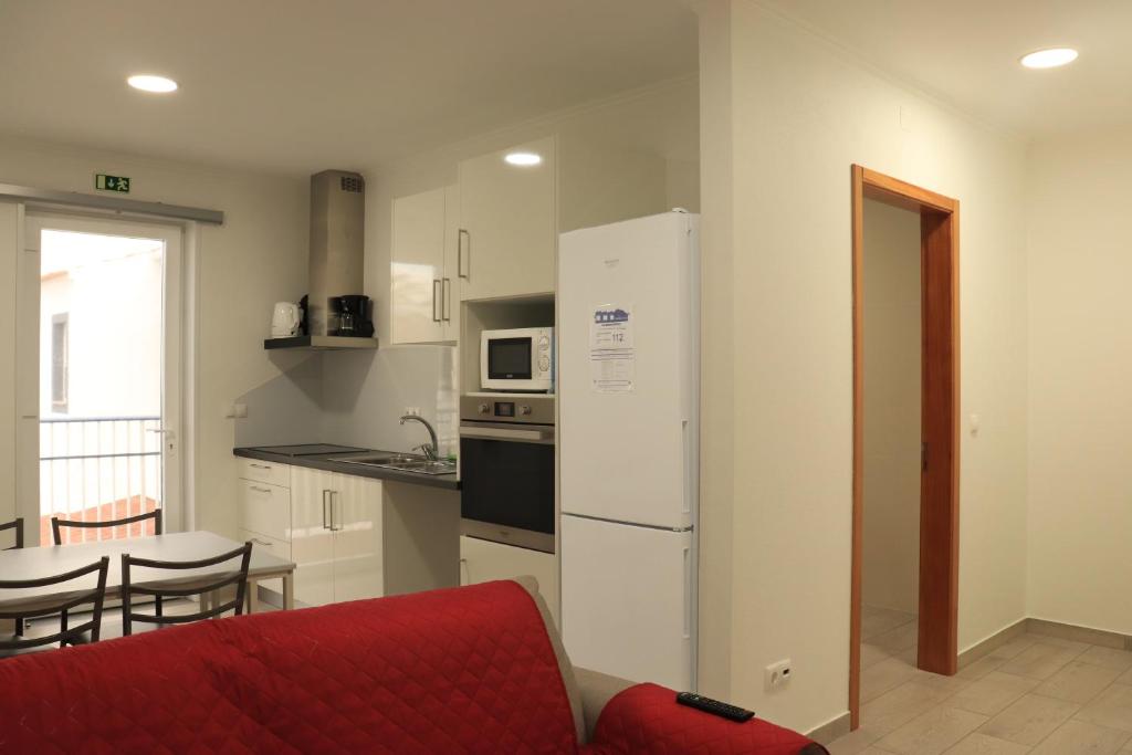 a kitchen with a white refrigerator and a red couch at Faial Marina Apartments 2 in Horta