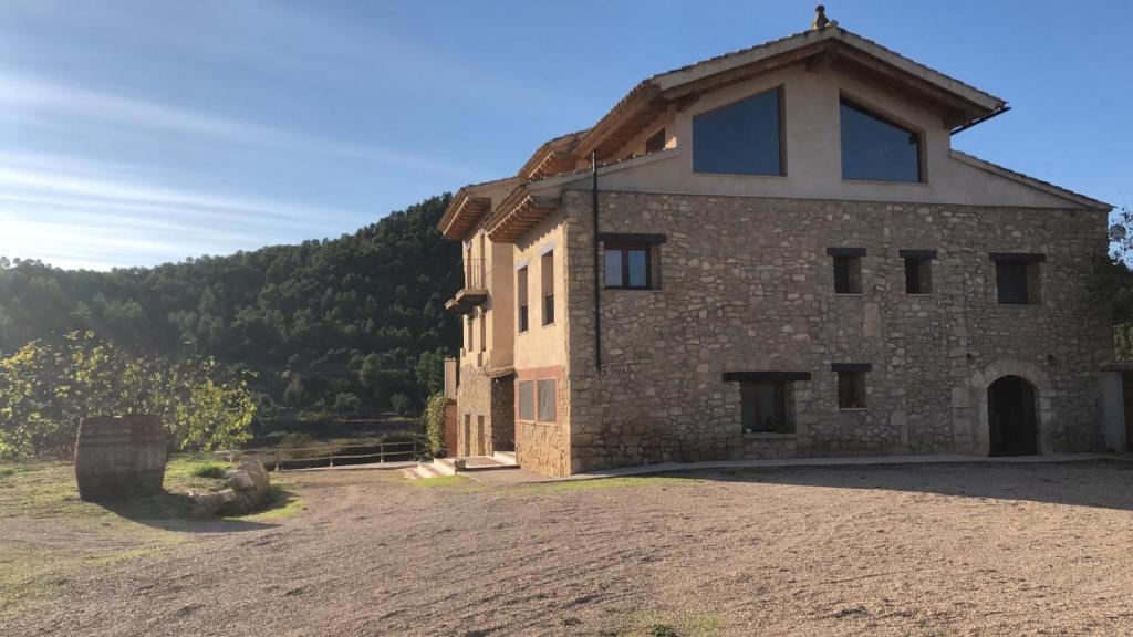 un gran edificio de piedra con una colina en el fondo en MASIA MAS DE LA CREU, en Valderrobres