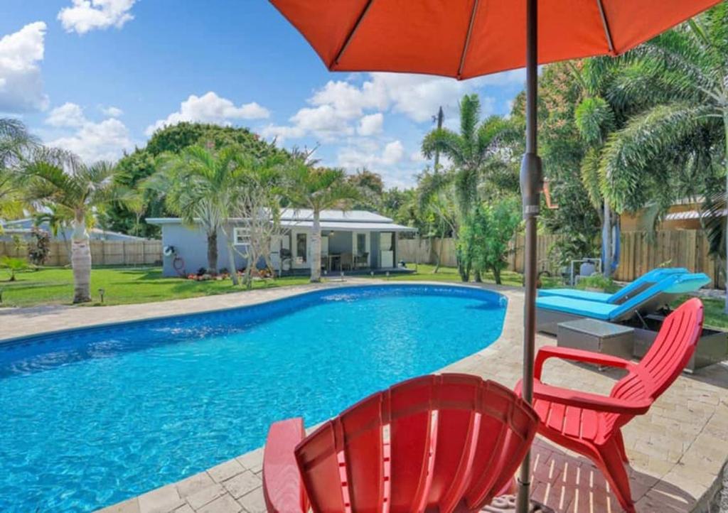 a pool with two red chairs and an umbrella at Wilton Palms - Unit 102 & 103 in Fort Lauderdale