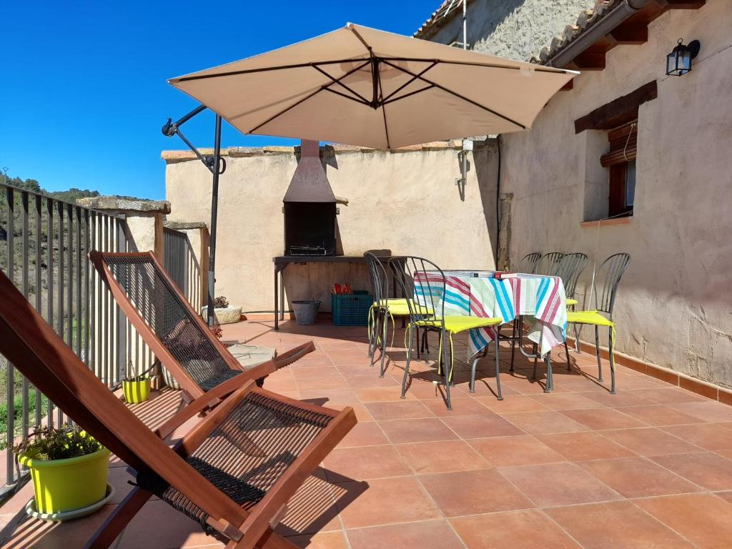 eine Terrasse mit einem Tisch, Stühlen und einem Sonnenschirm in der Unterkunft Casa Leandron in Murillo de Gállego