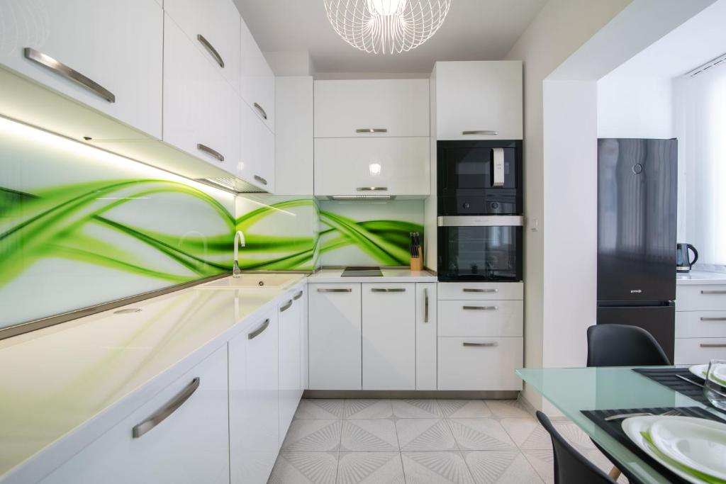 una cucina con armadi bianchi e parete verde di BGApartments - Momina Salza a Varna