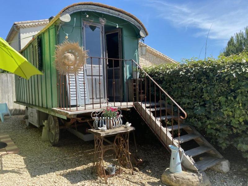 a green train car with a staircase in a yard at Une roulotte à la campagne in Saint-Just-et-Vacquières