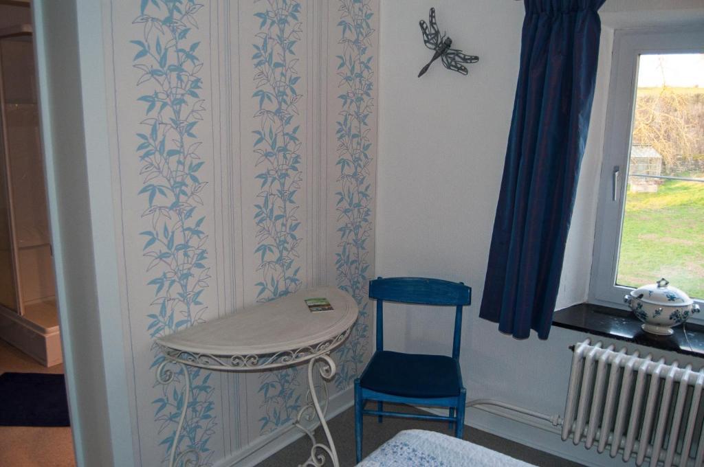 a room with a chair and a table and a window at Chambres d&#39;hôtes de la Quairelle in Gerpinnes