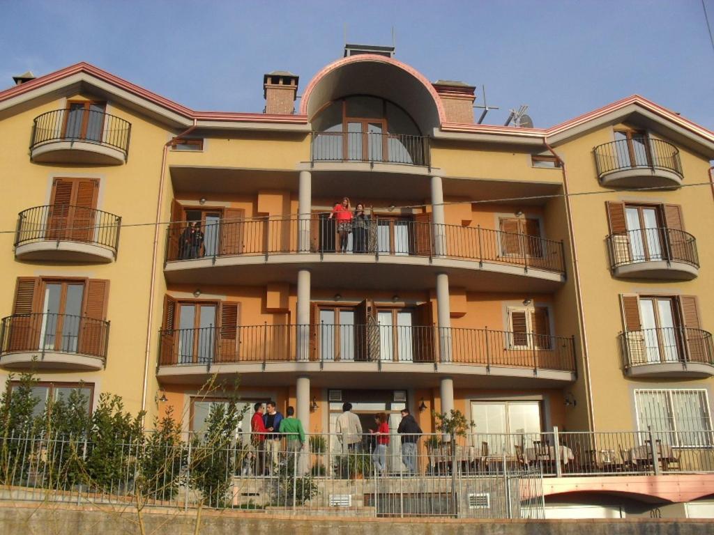 a large yellow building with people standing on the balconies at Hotel Giardino San Michele in Vallo della Lucania