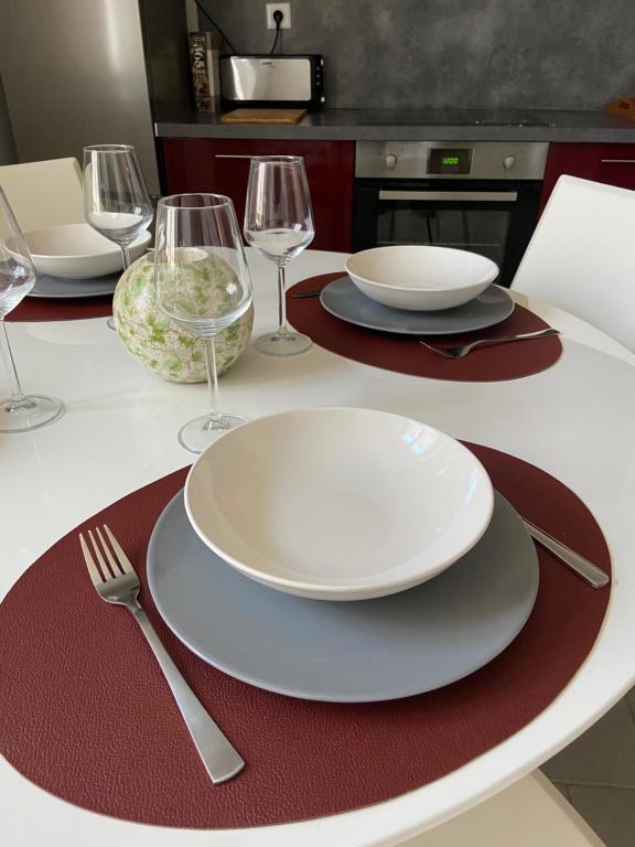 einen Tisch mit weißen Tellern und Weingläsern darauf in der Unterkunft Confortable duplex au cœur de la campagne Picarde à 1h de Paris in Biermont