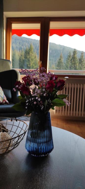 a blue vase with purple flowers on a table at Ferienwohnung Tannenballett im Schwarzwald in Baiersbronn