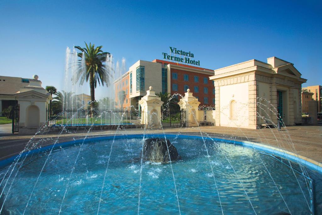 una fontana di fronte a un hotel con un edificio di Victoria Terme Hotel a Tivoli Terme