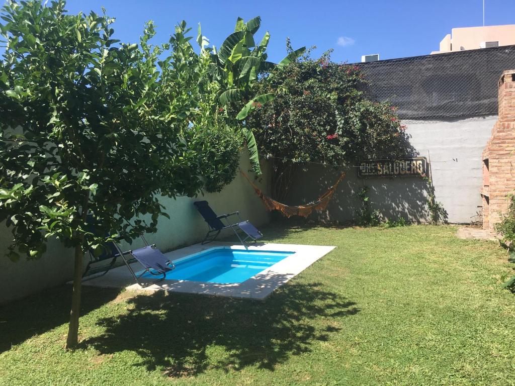 een zwembad in een tuin met twee stoelen en een boom bij Casa con pileta Aeropuerto Circunvalación Kempes Quorum -cambio oficial- in Cordoba