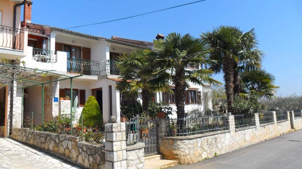 a house with palm trees and a stone fence at Apartment in Rovinj/Istrien 11560 in Štanga
