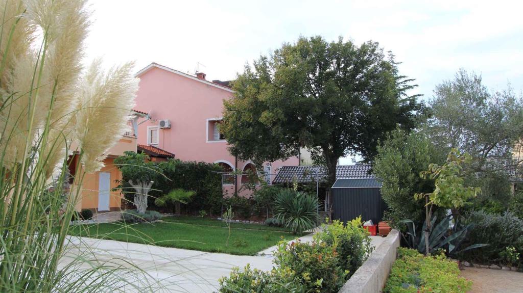 a pink house with trees and plants in a yard at Apartment in Malinska/Insel Krk 14682 in Porat