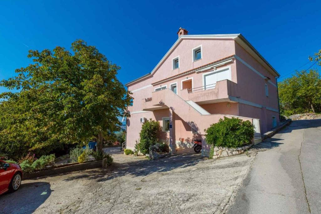 a pink house with a car parked in the driveway at Apartment in Crikvenica 14049 in Klanfari