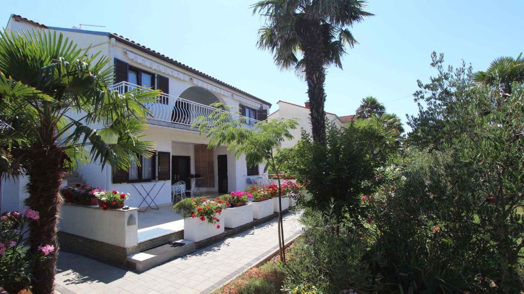 a white house with a palm tree and flowers at Apartment Malinska,Krk, Primorje-Gorski Kotar 8 in Vantačići