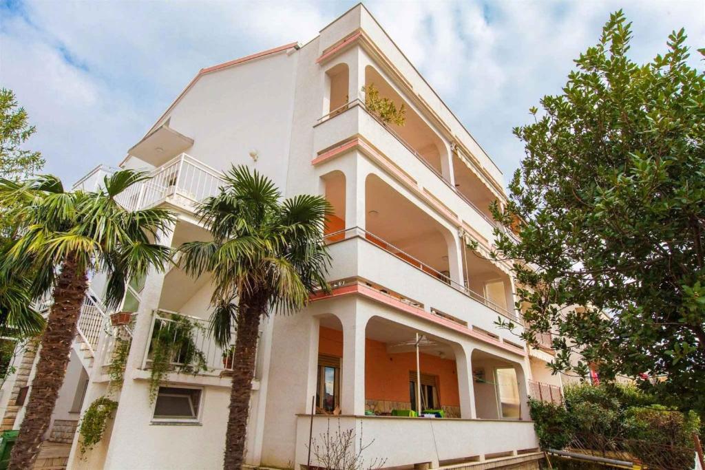 a white building with palm trees in front of it at Apartment in Crikvenica 14237 in Crikvenica