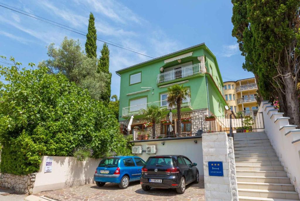 two cars parked in front of a green house at One-Bedroom Apartment in Crikvenica 8 in Dramalj