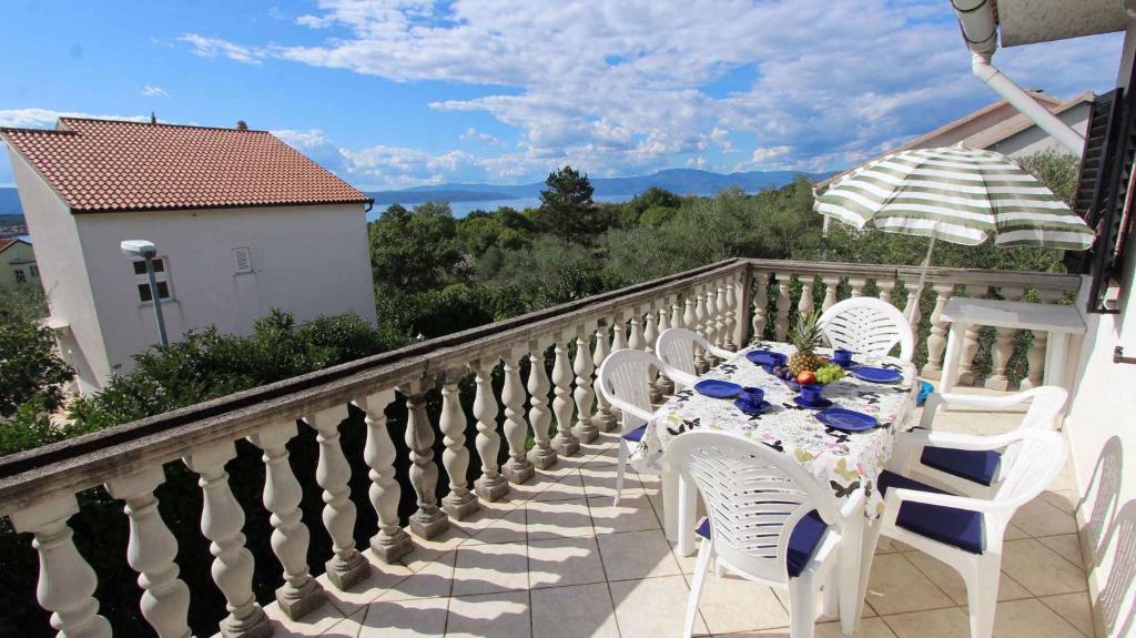a table and chairs on a balcony with an umbrella at Apartment in Malinska 12 in Sveti Vid-Miholjice