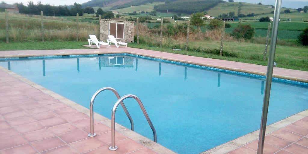uma grande piscina com duas cadeiras brancas em StarHome em San Miguel de Meruelo